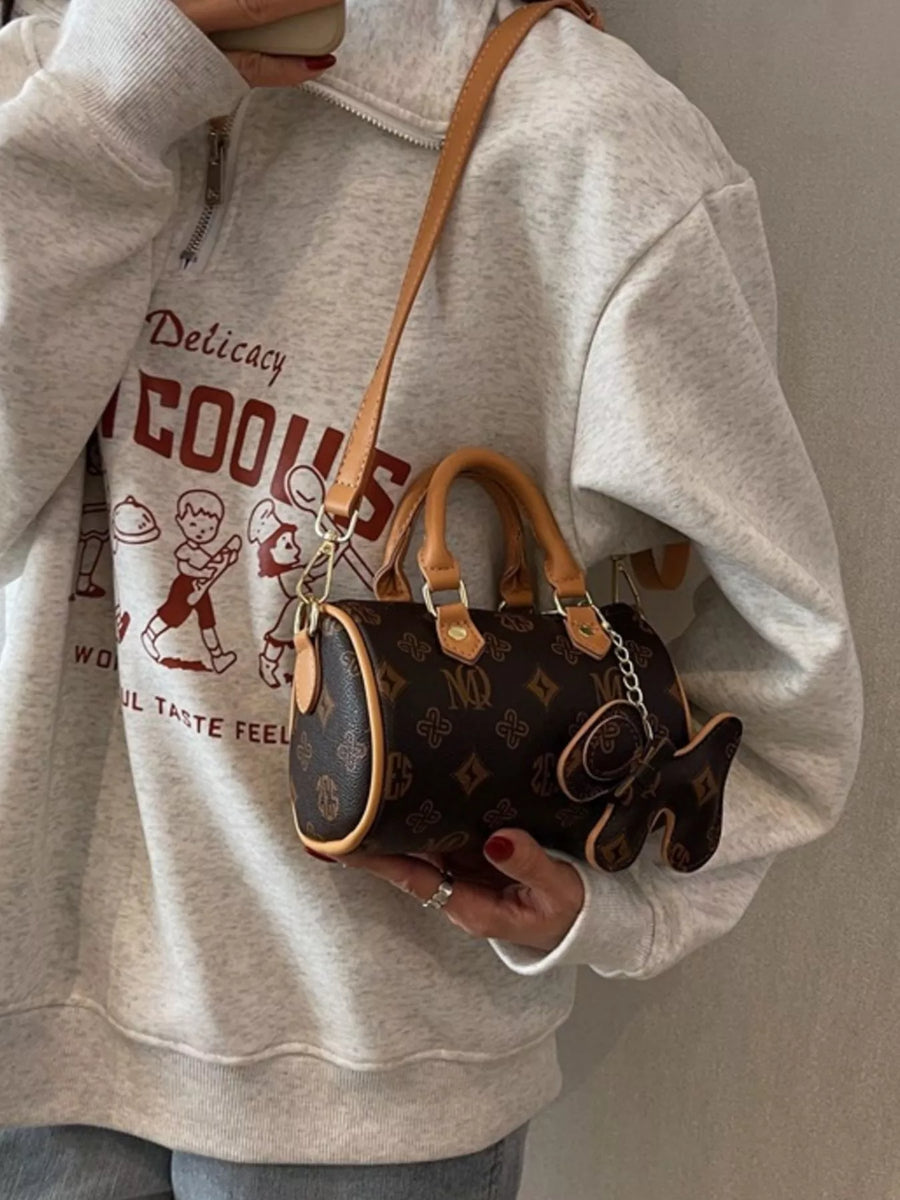 Mini barrel crossbody bag in brown with monogram pattern and butterfly charm.