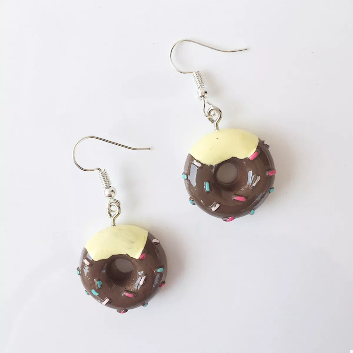 Dark brown donut dangle earrings with yellow icing and colorful sprinkles.