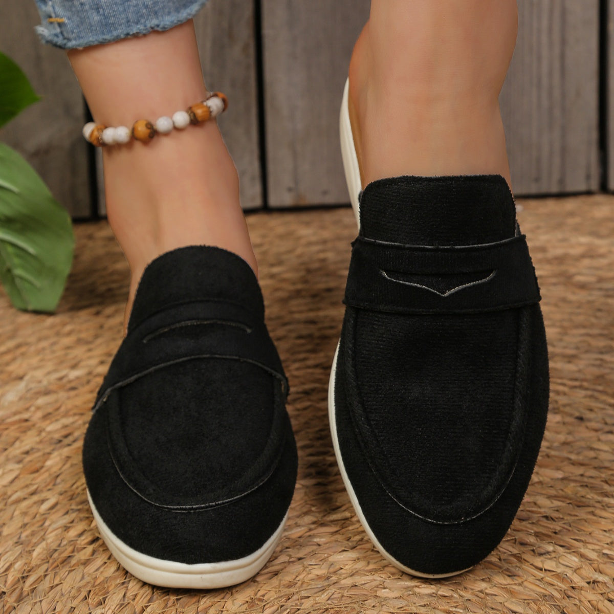 Black textured round toe slip-on loafers with a backless design and decorative strap detail.