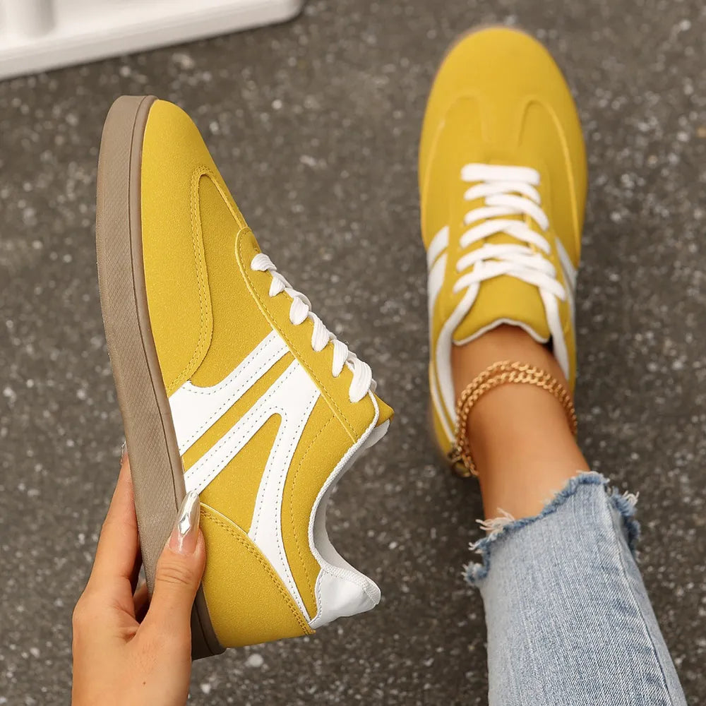 Yellow suede sneakers with white chevron detail and white laces.