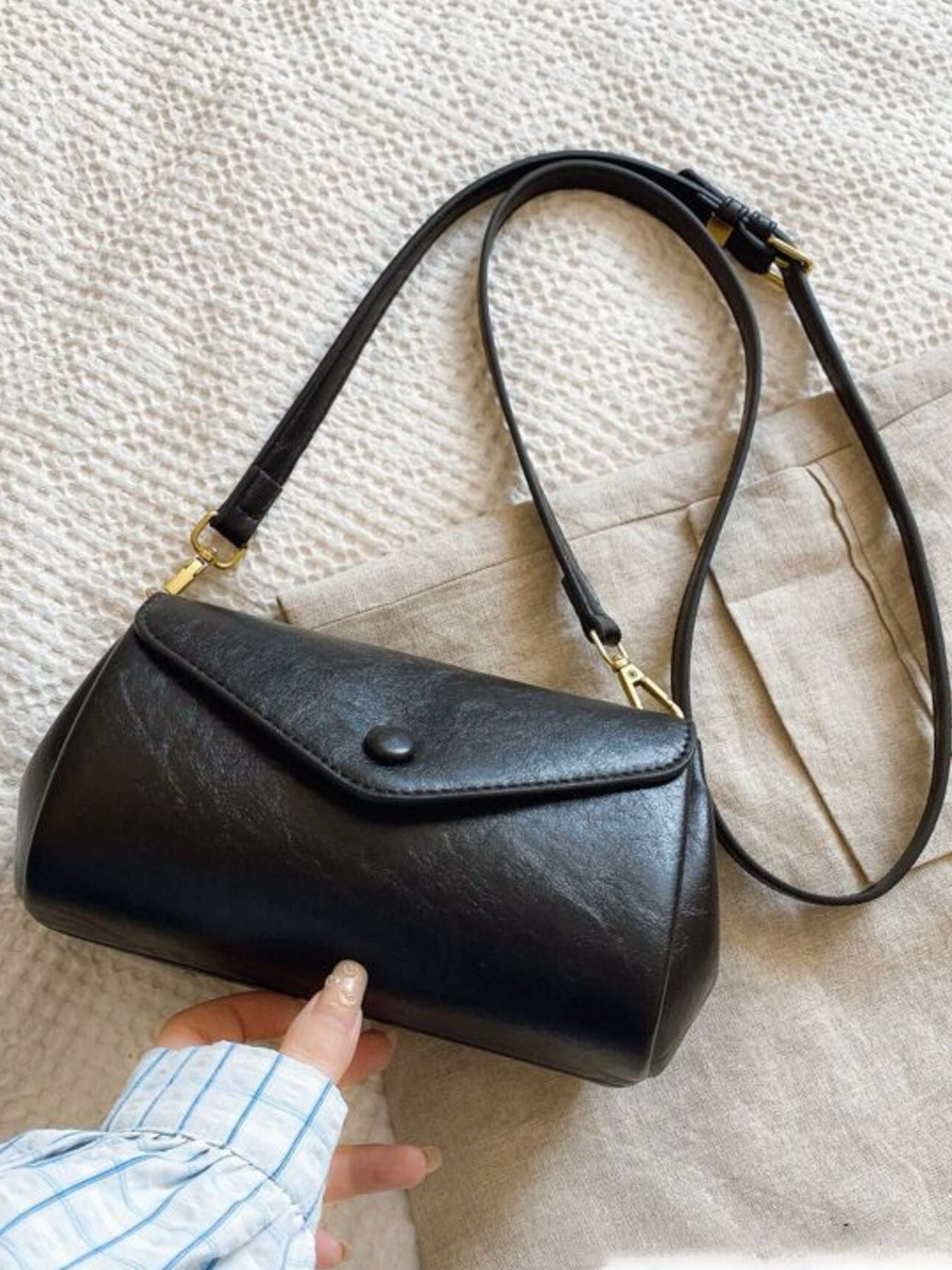 Black mini pu leather flap crossbody bag with button closure and adjustable strap.