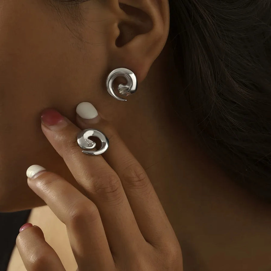 Silver sculptural zirconia swirl stud earrings and matching ring.