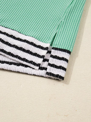 Turquoise long-sleeve top with twisted ribbing and black and white striped cuffs.