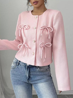 Pink textured jacket with bow details and pearl buttons, crew neck, long sleeves.