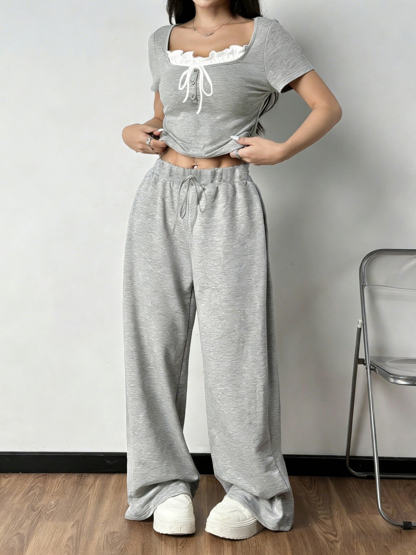 Grey tie-front cropped top with ruffled neckline and drawstring wide-leg pants set.
