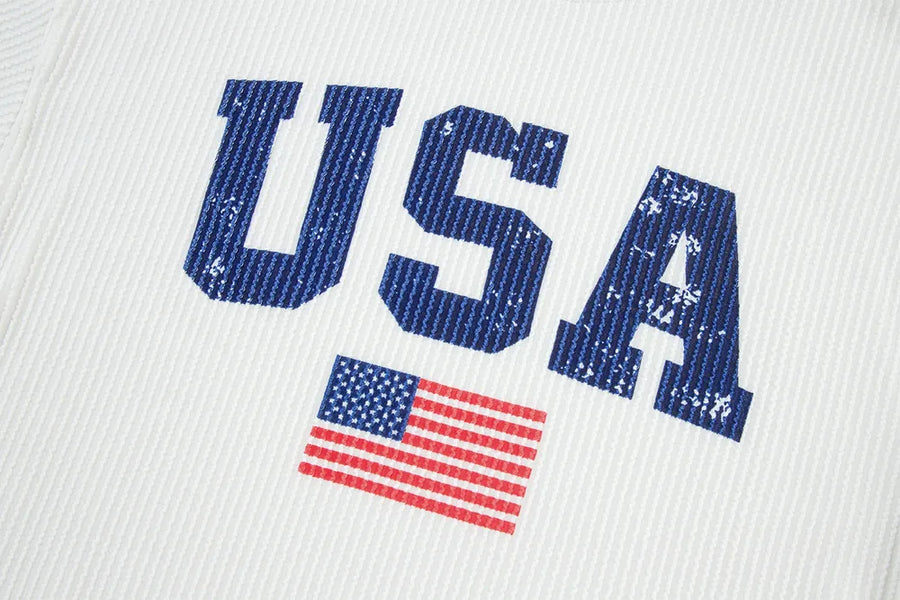 White ribbed knit sweatshirt with distressed blue USA graphic and American flag detail.