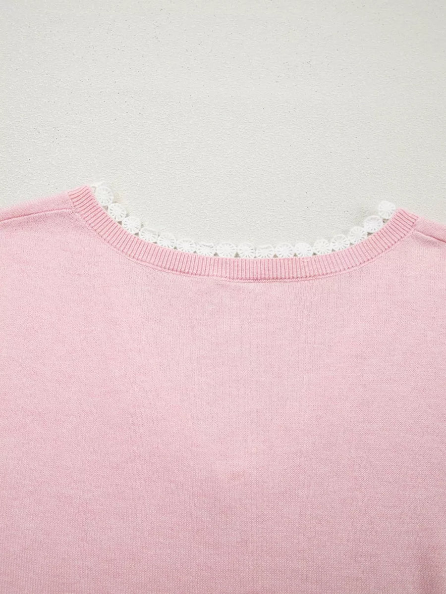 Pink knit top with delicate white lace trim at the V-neckline.