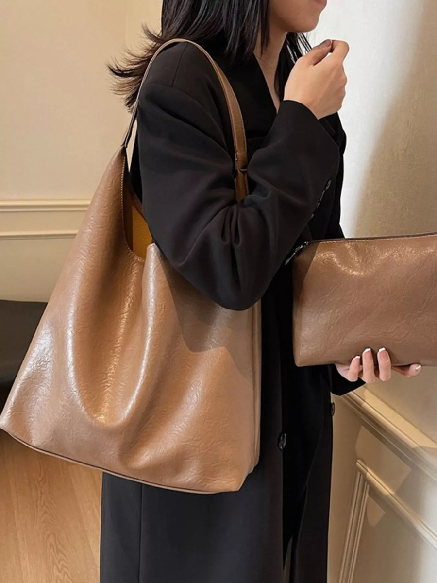 Brown sculptural PU leather tote bag with matching pouch, worn with a black blazer.