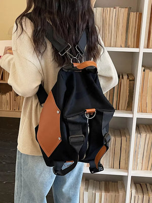Black nylon crossbody bag with contrast tan pocket and leather trim.