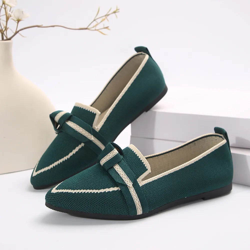 Dark green knit bow loafers with pointed toe and cream trim.