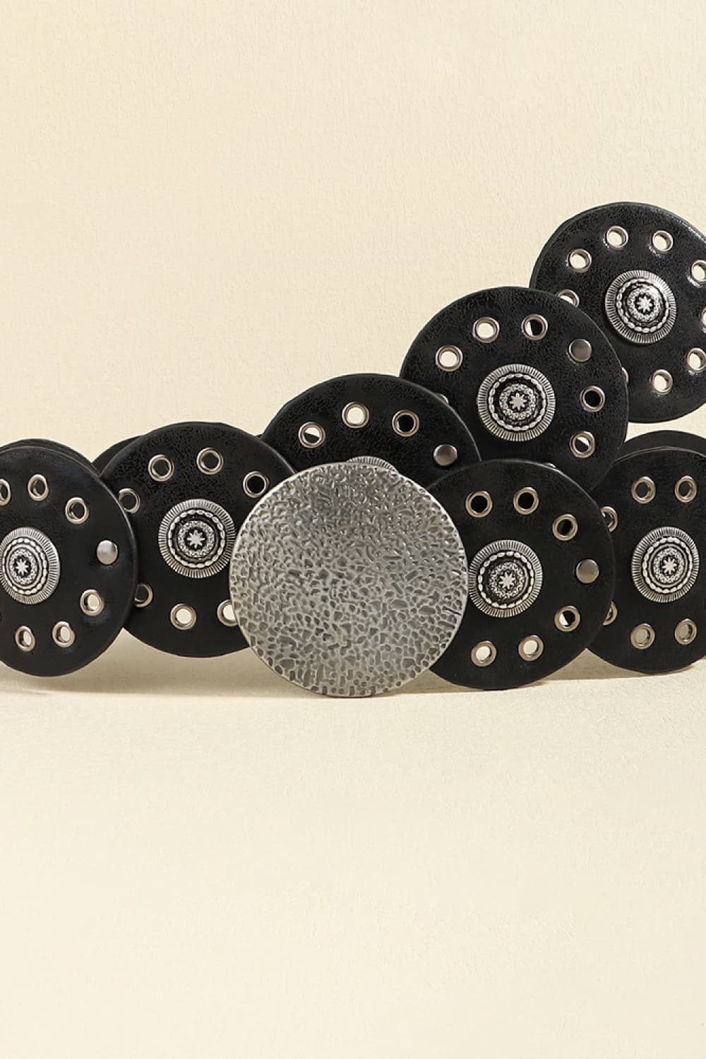 Black faux leather belt with round silver-tone disc embellishments and eyelet details