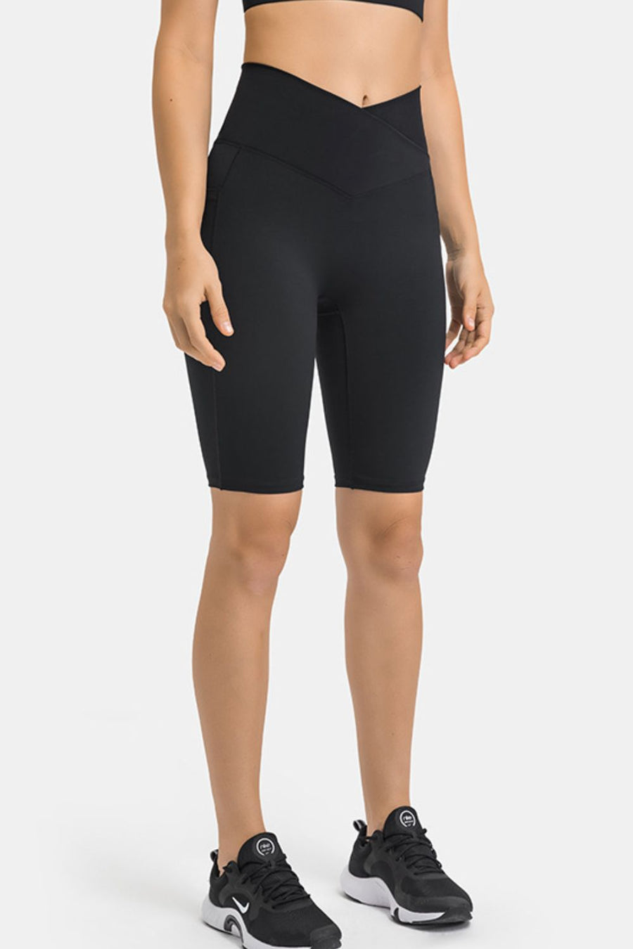 Black V-waist pocketed performance biker shorts with a high rise and mid-thigh length.