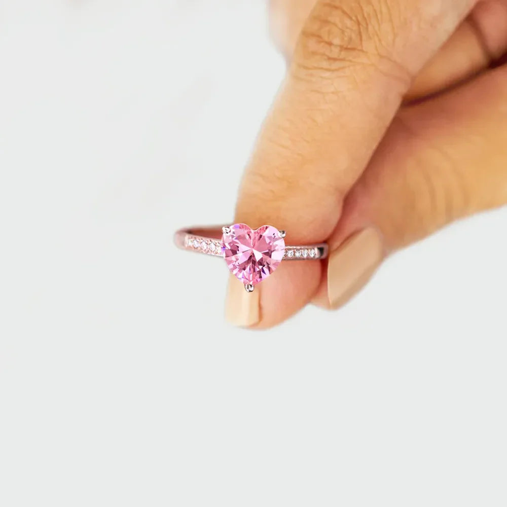 Rose gold ring with a pink heart cut pavé stone and small clear stones on the band.