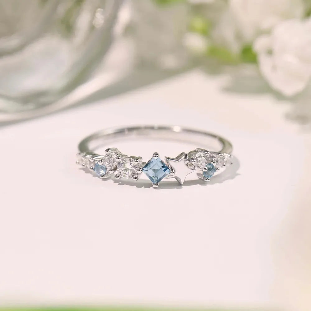 Silver ring with celestial cluster of blue square and clear round cubic zirconia stones and star details.