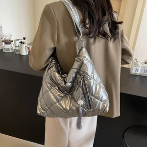 Diamond quilt padded shoulder bag in gray with a tassel detail and zippered pocket.