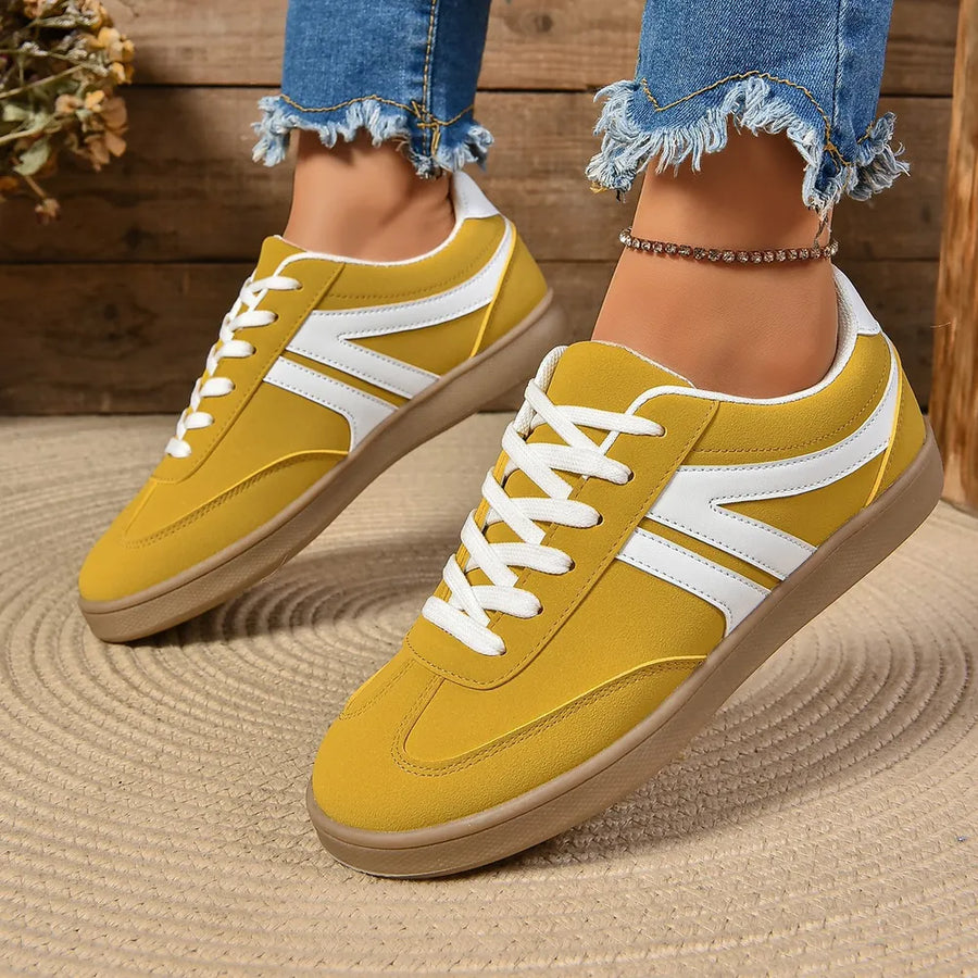 Yellow suede sneakers with white chevron detail and lace-up closure.