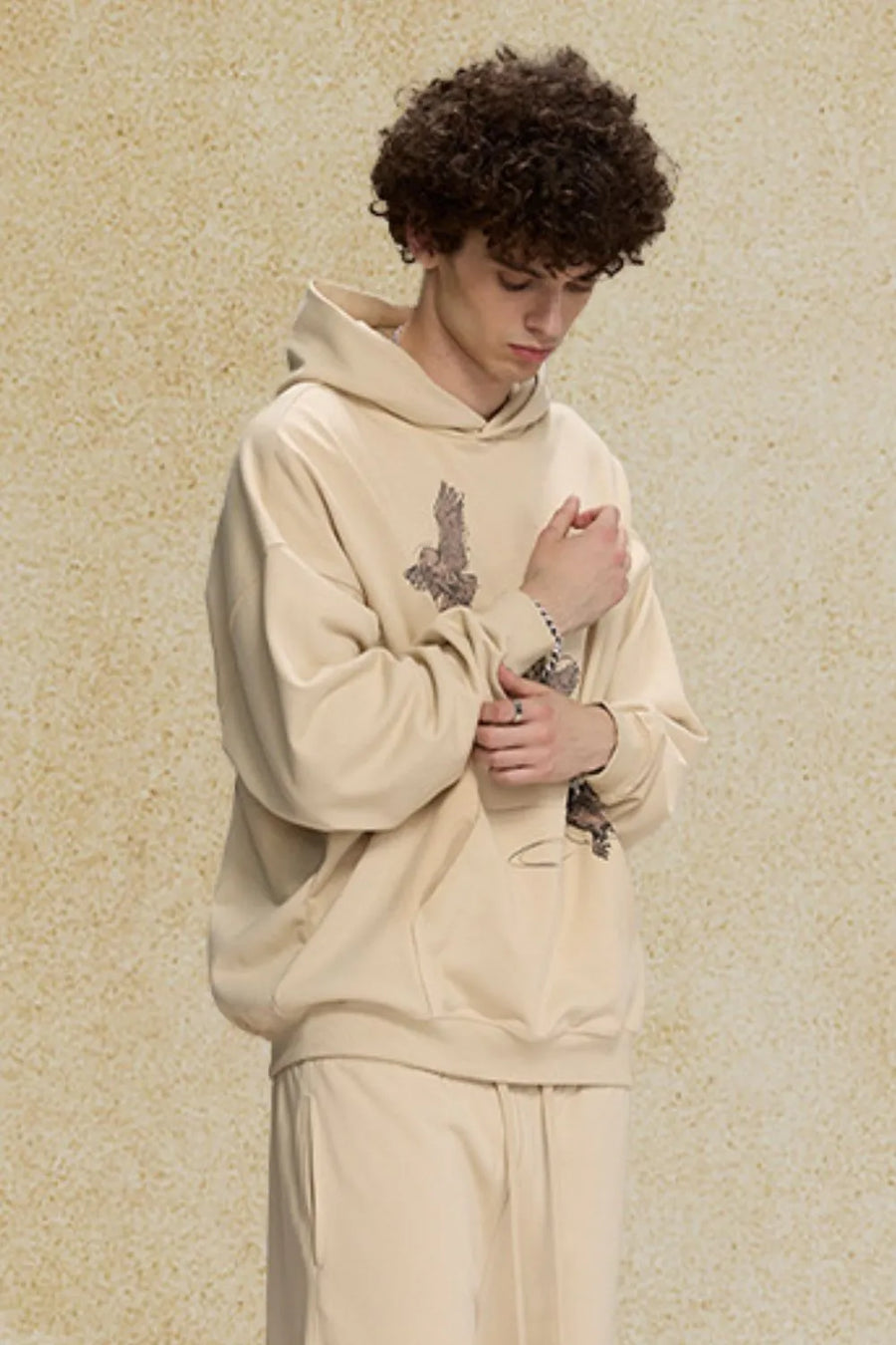 Khaki relaxed fit hoodie with embroidered bird graphic on chest and sleeve.