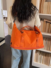 Orange nylon travel bag with buckle straps and adjustable shoulder strap.
