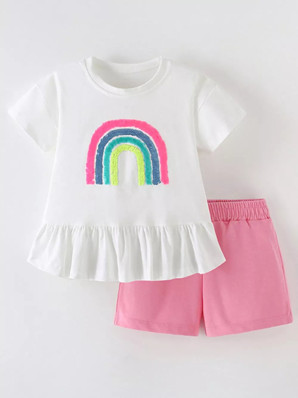 White t-shirt with rainbow graphic and ruffled hem with pink shorts