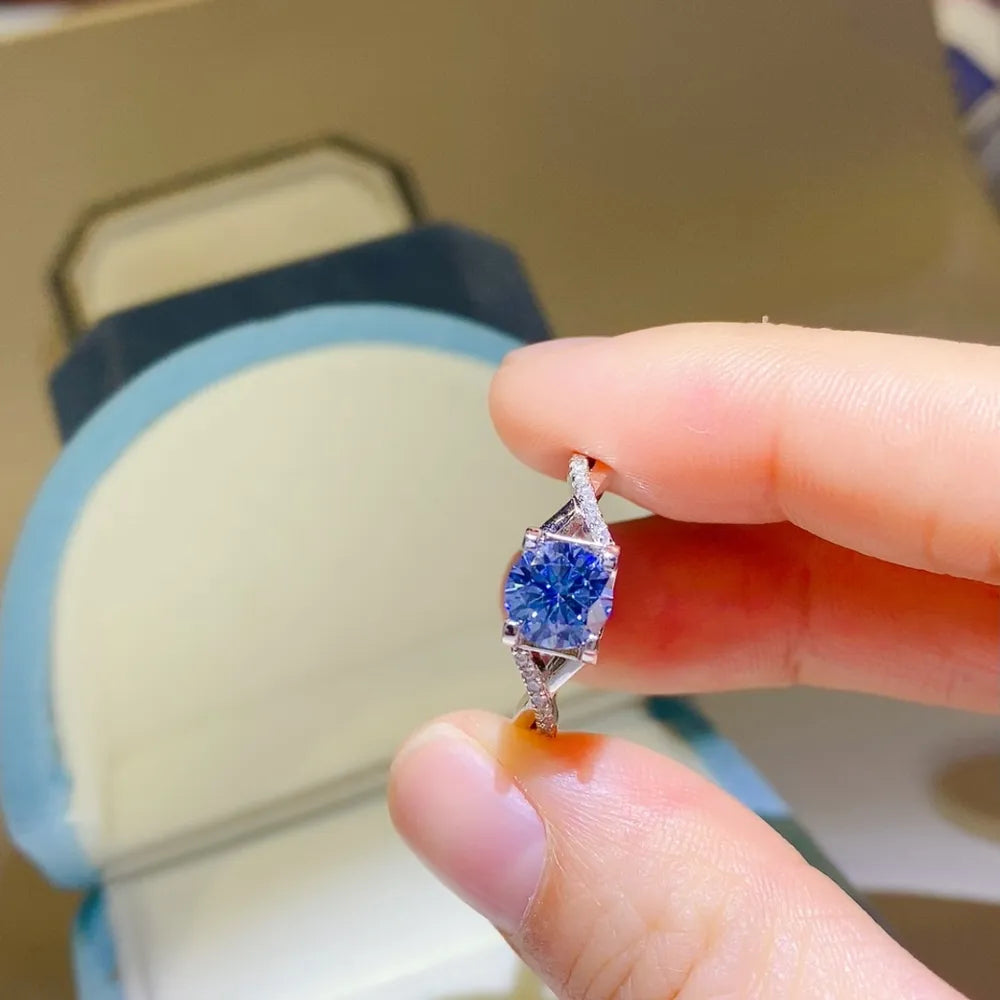Silver twisted pavé moissanite engagement ring with a bright blue center stone.