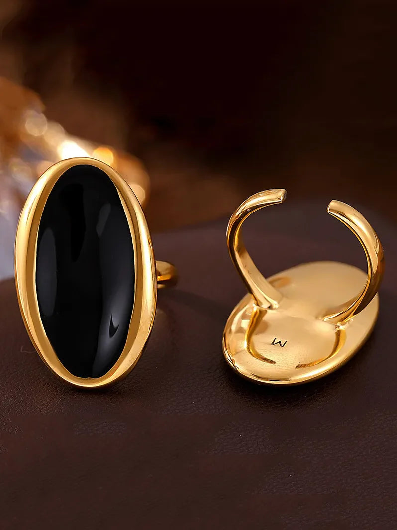 Gold cocktail ring with sculpted oval black onyx stone and adjustable band.