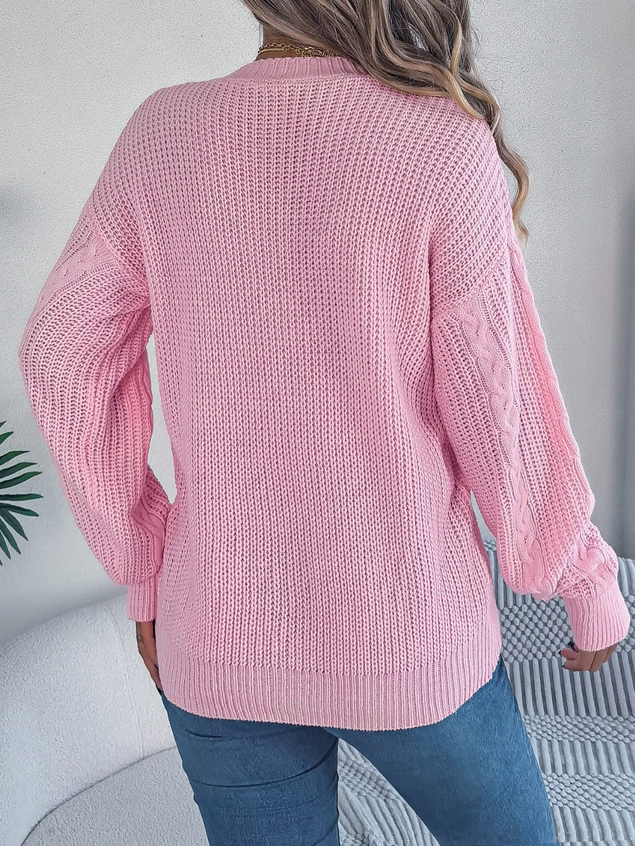 Blush pink cable knit cardigan with balloon sleeves and buttoned front, acrylic.