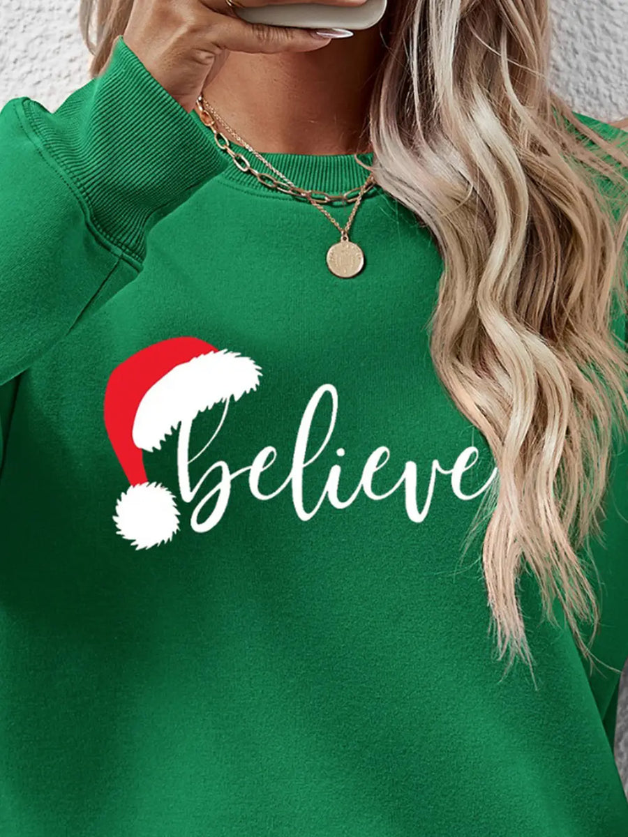 Green raglan sweatshirt with white "believe" text and Santa hat graphic