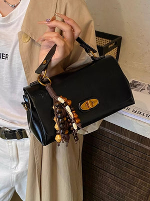 Compact black pu leather shoulder bag with decorative beaded tassel and gold clasp