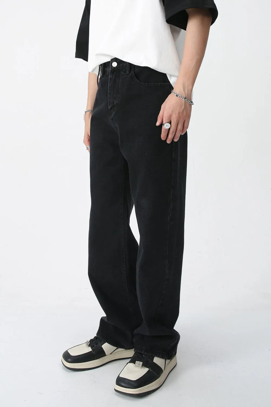 Wide-leg black denim trousers with a relaxed fit, styled with sneakers.