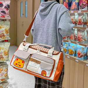 Cream travel organizer bag with orange trim, gingham pattern, and cute bear applique.