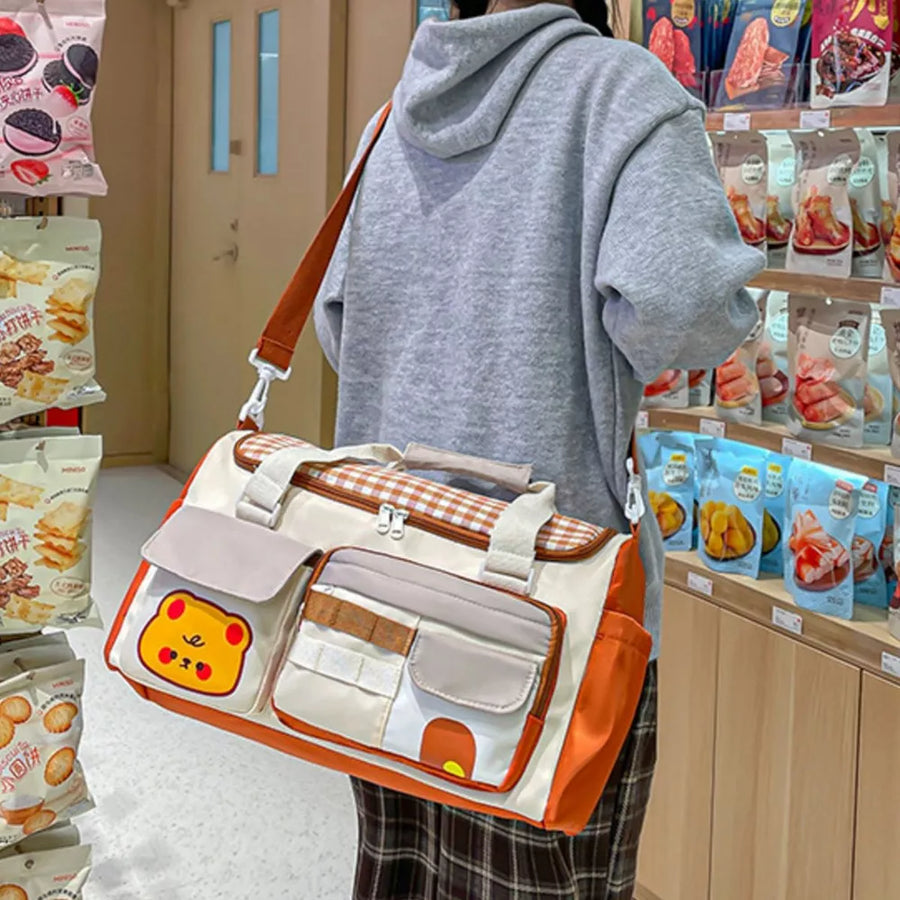 Cream travel organizer bag with orange trim, gingham pattern, and cute bear applique.
