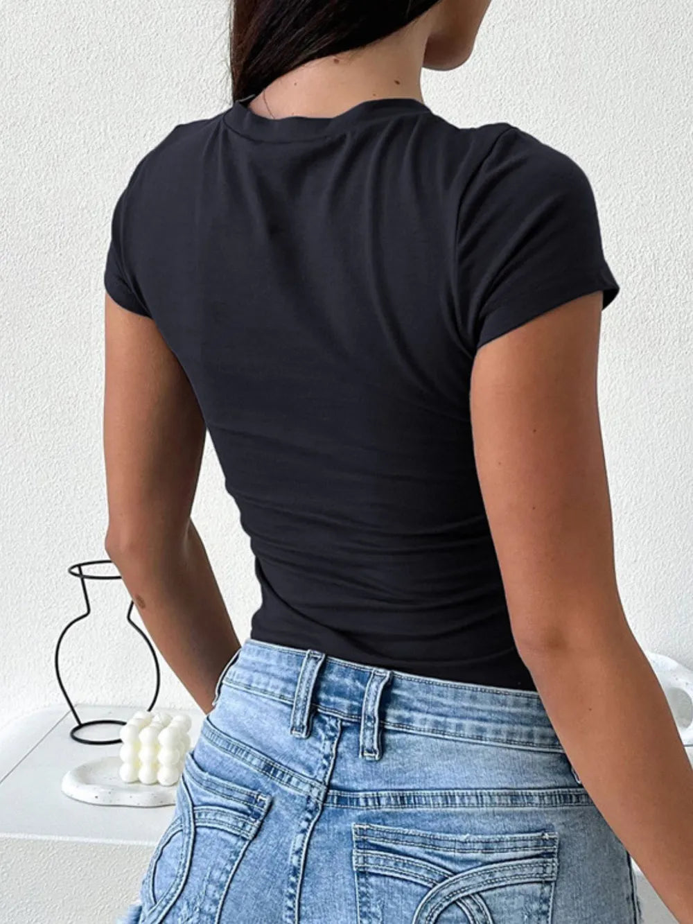 Black fitted t-shirt with short sleeves and a round neckline.