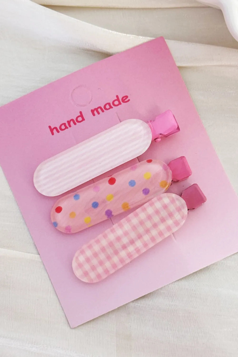 Pastel pink hair clips trio with stripes, polka dots, and gingham patterns.