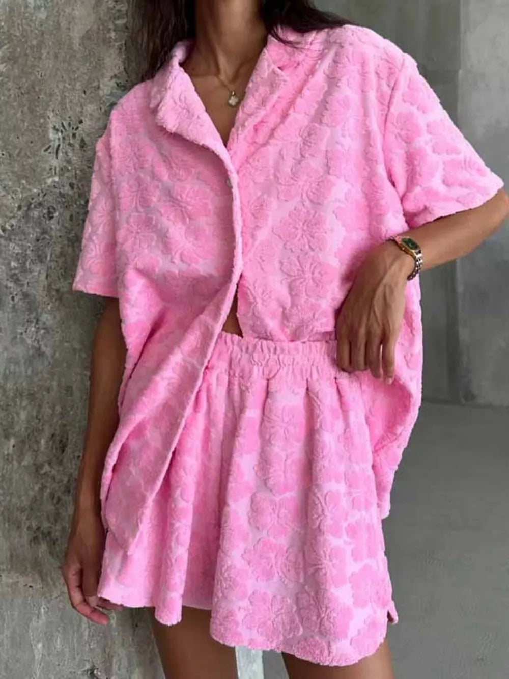 Pink textured floral button-up shirt and shorts set with short sleeves and elastic waist shorts.