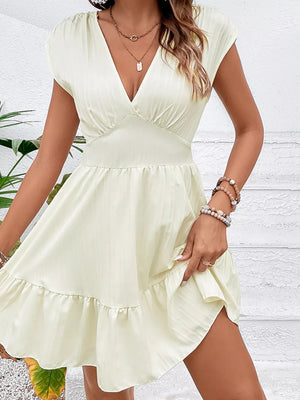 Tiered cap sleeve mini dress in white with a V-neck and ruffled hem.