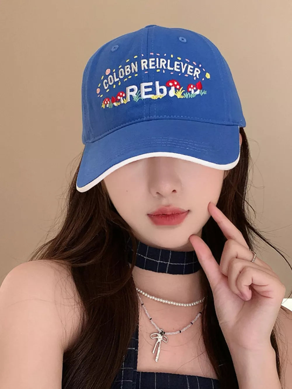 Blue baseball cap with playful embroidered mushrooms and text, white trim