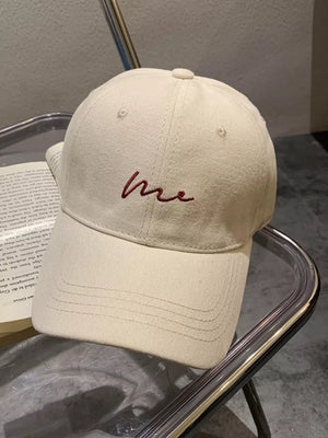 Cream white cotton baseball cap with curved brim and embroidered "me" detail.