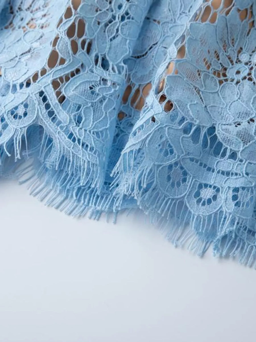 Blue lace dress detail with fringed hem and intricate floral pattern.