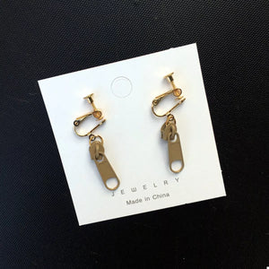 Khaki zipper dangle clip-on earrings with gold-tone hardware.