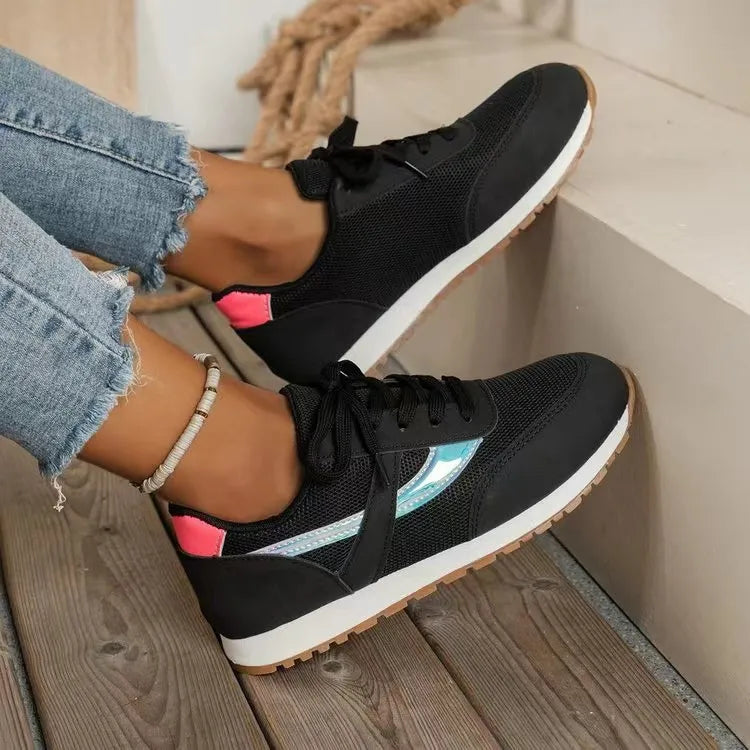 Black mesh runners with iridescent side panels and pink heel accents.