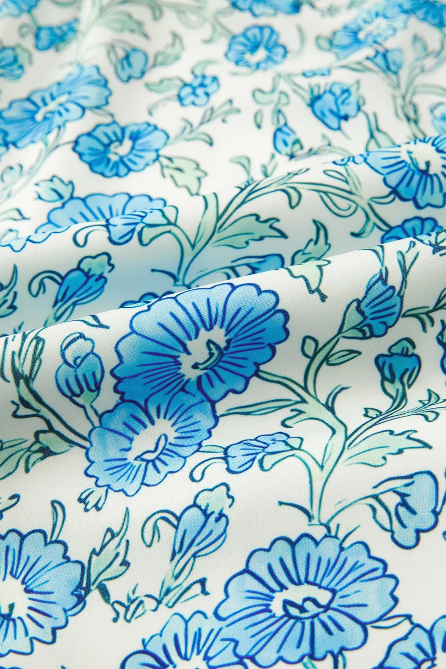 Botanical print mini dress in white with blue flowers and green leaves, made of polyester.