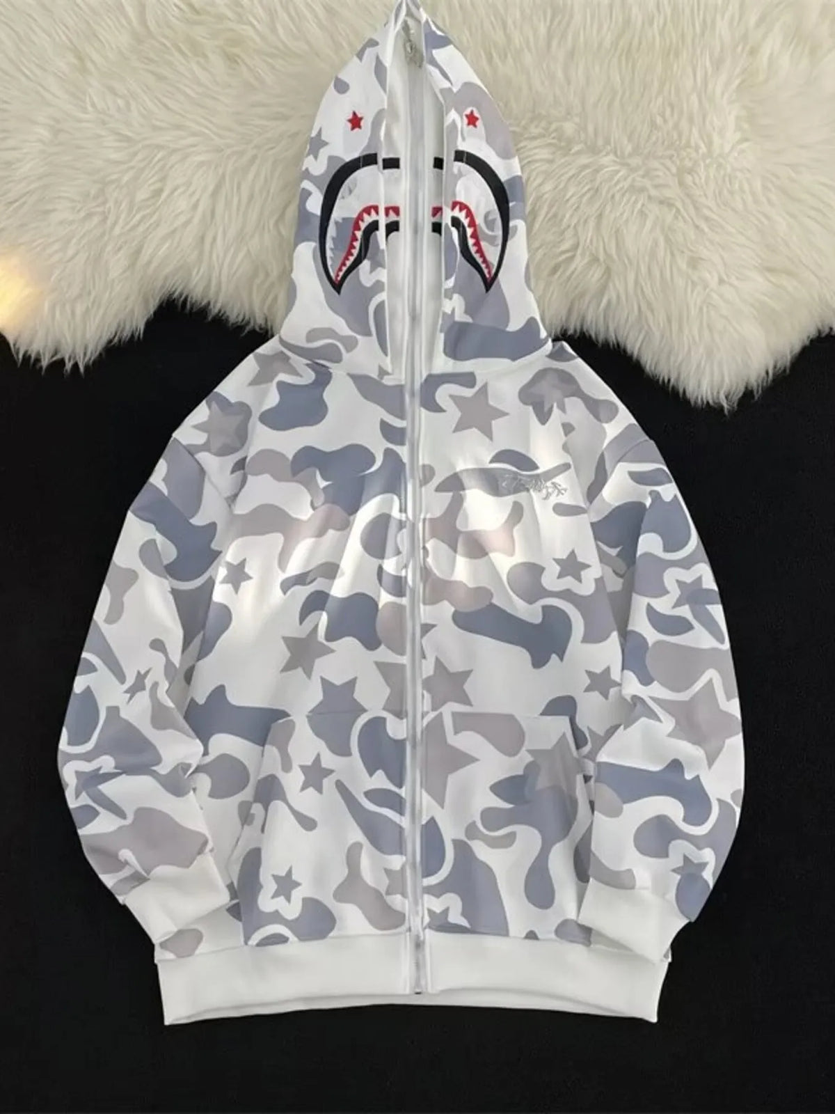 Off-white camo print zip-up hoodie with shark graphic on hood and star details.