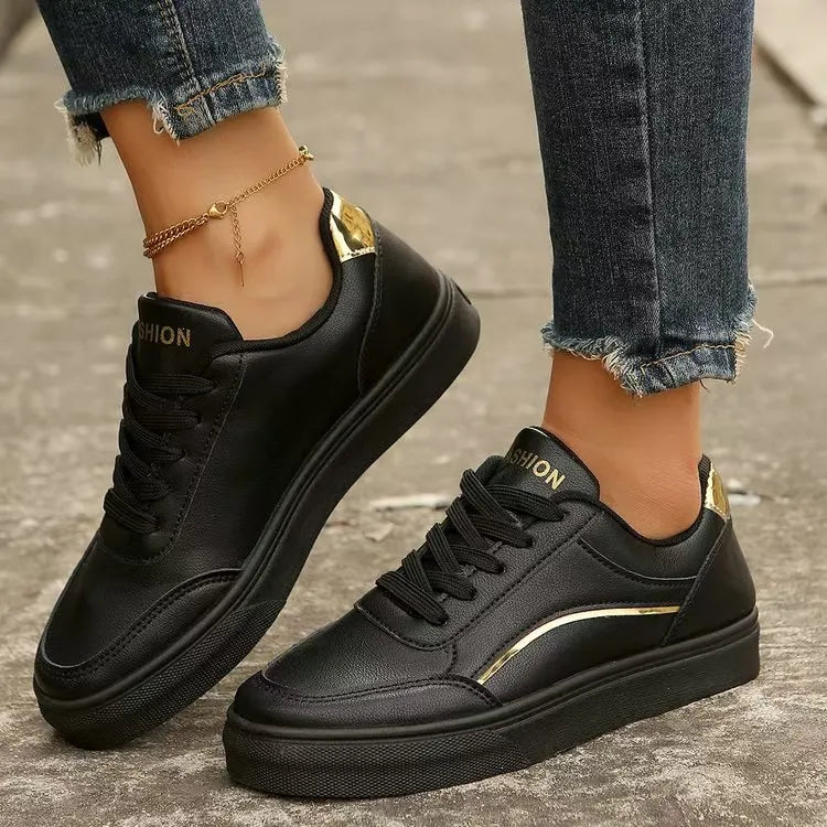 Black leather sneakers with gold metallic trim and heel detail.