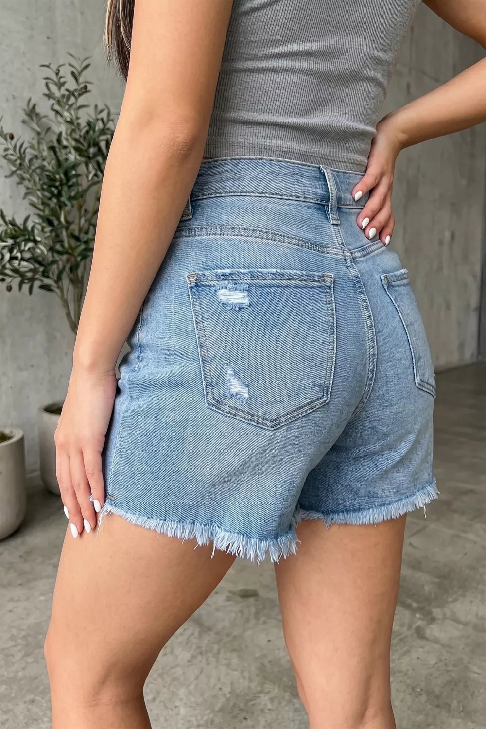 Light wash denim shorts with distressed details and a raw hem.
