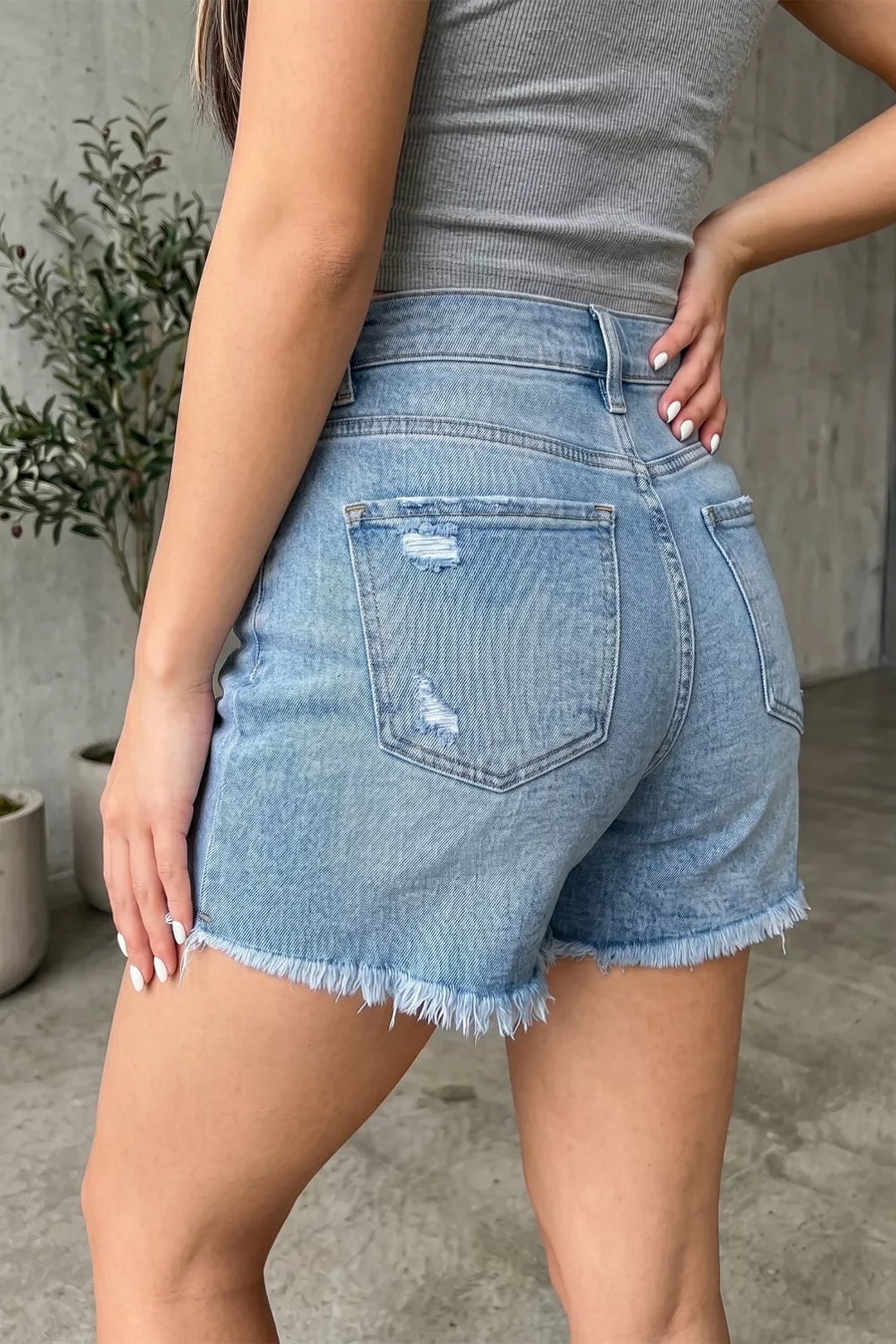 Light wash denim shorts with distressed details and a raw hem.