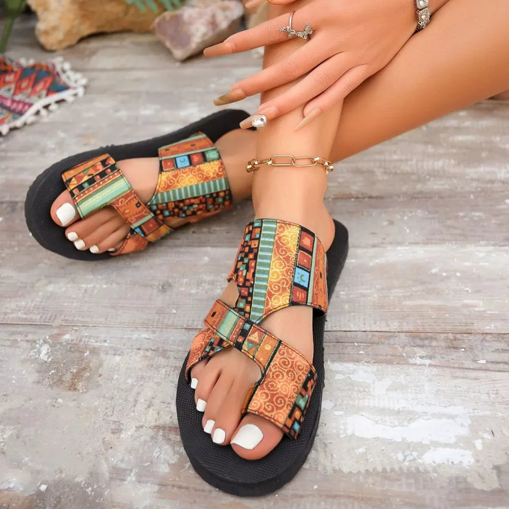 Geometric patterned toe loop sandals with colorful straps and black soles.