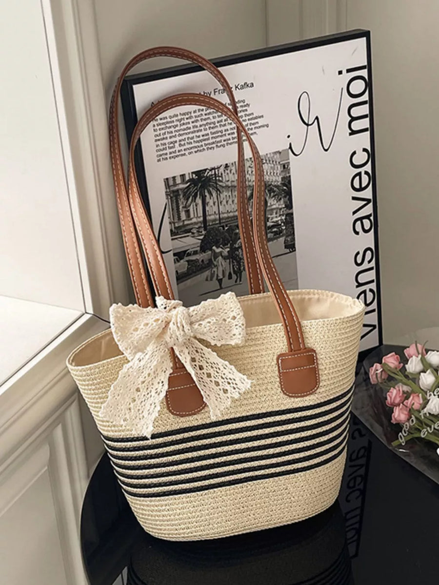 Charming straw shoulder bag with black stripes and lace bow detail