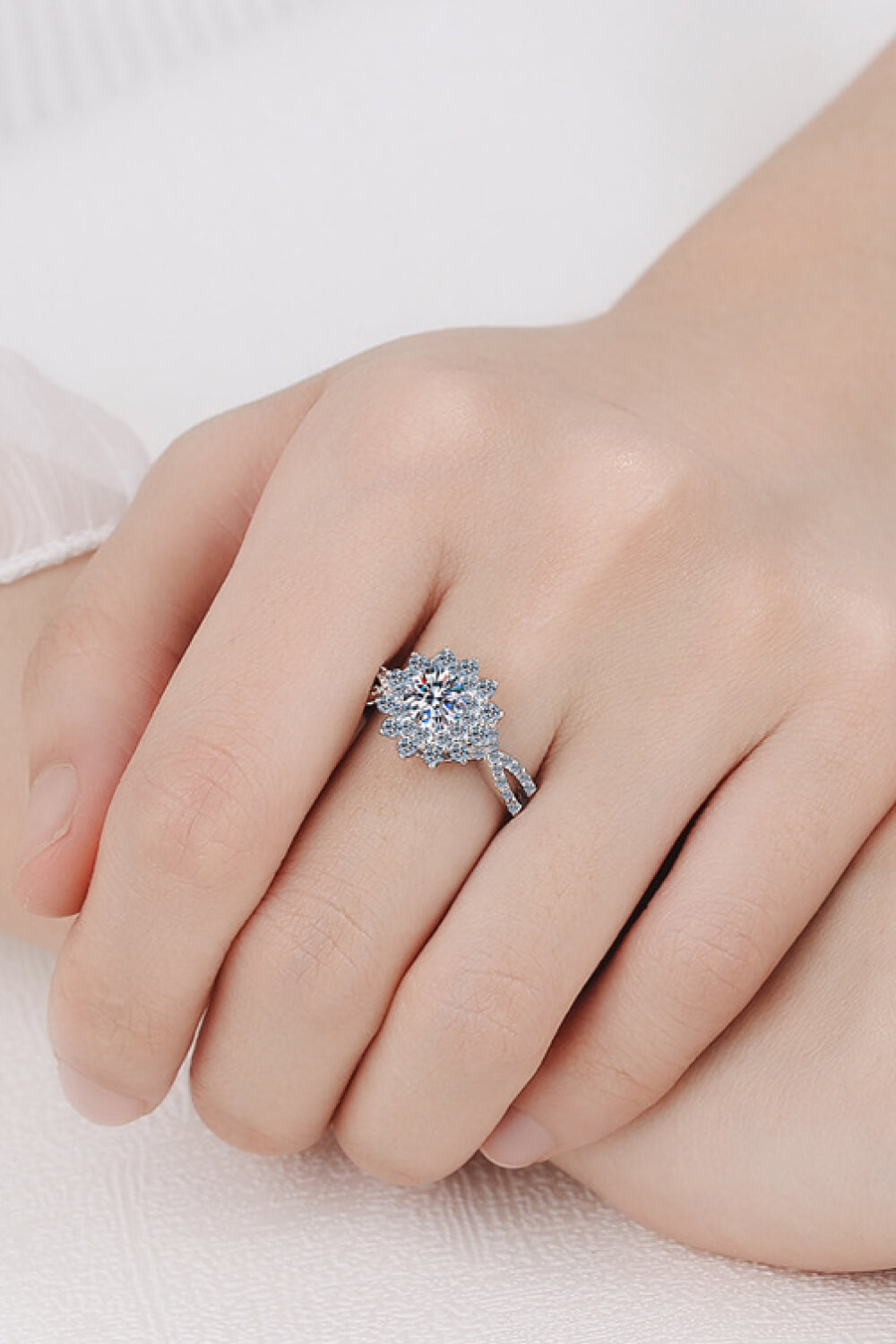 Silver moissanite ring with halo and twisted band detail on hand