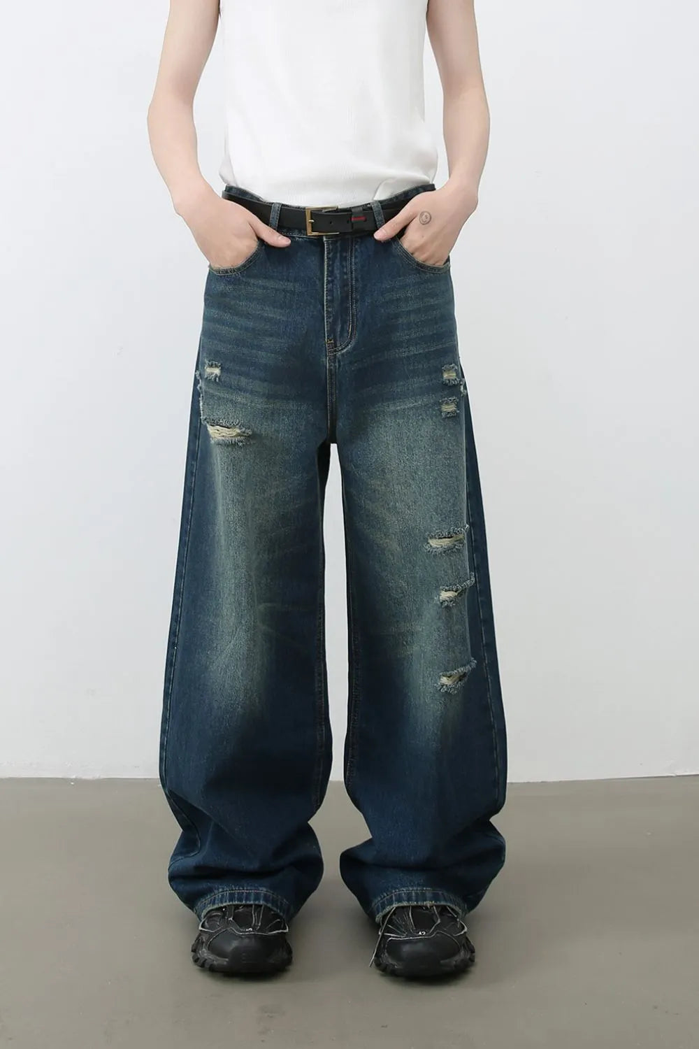 Distressed baggy dark wash denim jeans with wide legs and ripped details.