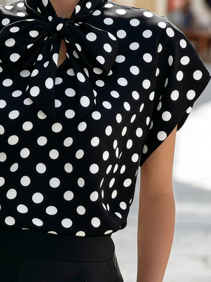 Black polka dot polyester shirt with cap sleeves and a large bow tie neck.